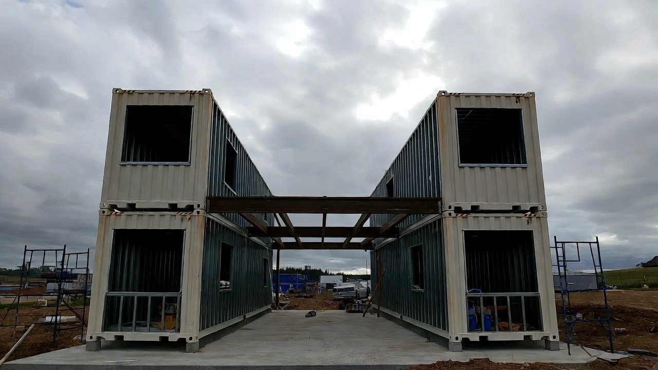 Shipping container home under construction with window openings cut