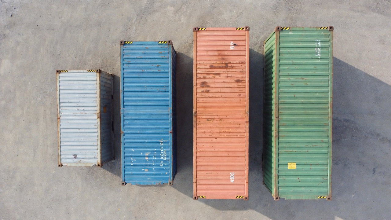 Aerial view of four shipping containers of different sizes in a row